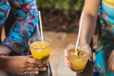 Two people holding drinks with paper straws